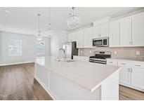 Bright kitchen features a large island with stone countertops and stainless steel appliances at 1204 Holding Village Way, Wake Forest, NC 27587