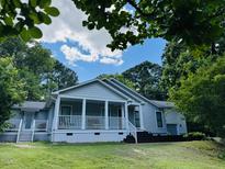 Charming one-story home with a spacious front porch, complemented by lush landscaping and mature trees at 135 Weatherbend, Pittsboro, NC 27312