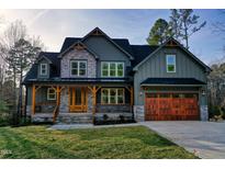 Charming two-story home featuring a stone facade, wooden accents, and a well-manicured lawn at 414 S Sb Harrison Ln, Henderson, NC 27537