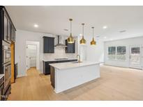 Bright kitchen featuring an island with sink, modern stainless appliances, and wood floors at 3301 Oakfields Rd # 2, New Hill, NC 27562