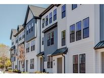 Charming townhome exterior featuring white siding and modern architectural details, with black framed windows at 6420 Tanner Oak Ln, Raleigh, NC 27613