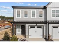 Charming two-story townhome featuring gray siding, a one-car garage, and a covered entryway at 709 Jamescroft Way, Rolesville, NC 27587