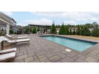 Backyard pool featuring a patio with lounge chairs, and a pergola with a dining table at 108 Scarlet Tanager Cir, Holly Springs, NC 27540