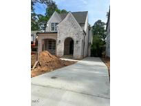 New construction showing a two-story home with white-painted brick and an arched entryway and a long concrete driveway at 3302.5 Hall Pl, Raleigh, NC 27607