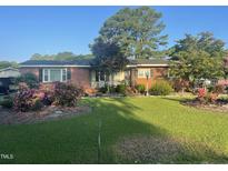 Charming brick home featuring mature landscaping and a well-manicured lawn at 229 Davis Mill Rd, Selma, NC 27576