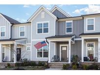Charming townhouse featuring a covered porch, American flag, and two-tone gray siding at 728 Silo Park Dr, Wake Forest, NC 27587