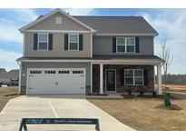 Charming two-story home features a two-car garage, stone accents, and a well-manicured lawn at 107 Wilderness Ct, Mebane, NC 27302