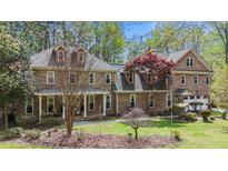 Inviting brick home featuring dormer windows, covered porch, and lush landscaping at 5317 Burning Oak Ct, Raleigh, NC 27606