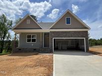 Charming new construction home featuring stone accents, a two-car garage, and a welcoming covered front porch at 114 Arundel Dr, Archer Lodge, NC 27527