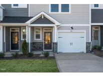 Charming townhome featuring stone accents, a one-car garage, and landscaped front yard at 207 Pond View Ct # 3, Fuquay Varina, NC 27526
