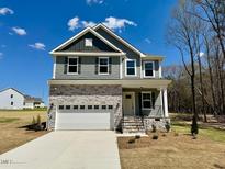 Charming two-story home with stone accents, attached garage, and well-maintained front yard at 45 Covey Rise Way, Lillington, NC 27546