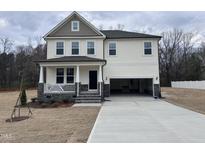 Charming two-story home boasts a welcoming front porch and an attached two-car garage at 63 Whimbrel Ct, Lillington, NC 27546