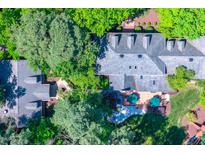 An aerial view of the home featuring a lush, green, landscaped backyard with mature trees and an inviting deck at 106 Alder Pl, Chapel Hill, NC 27517