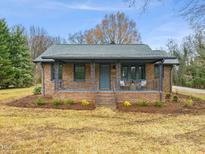 Charming brick home with a covered front porch and beautiful landscaping, perfect for curb appeal at 320 W Orange St, Hillsborough, NC 27278