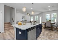 A stylish kitchen island featuring granite countertops and stainless steel appliances, complemented by hardwood floors at 3936 Well Fleet Drive, Fuquay Varina, NC 27526
