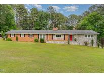 Charming brick and stone home featuring a well-manicured lawn and inviting red front door at 129 Jeffress Dr, Louisburg, NC 27549