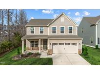 Two-story house with beige vinyl siding, stone accents, and a two-car garage at 321 Mason Oaks Dr, Wake Forest, NC 27587