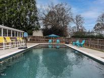 A backyard swimming pool with basketball hoop, umbrella, and various chairs for relaxing at 505 Harvard St, Raleigh, NC 27609