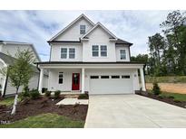 Charming two-story home featuring a red front door, white siding, and an attached two-car garage at 105 Windchime Ct, Fuquay Varina, NC 27526