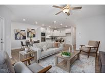 Open-concept living room with modern furnishings and wood flooring leading to the contemporary kitchen at 3856 Well Fleet Drive, Fuquay Varina, NC 27526
