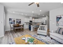 Open-concept living room features modern decor, ceiling fan, and a view of the kitchen at 3928 Well Fleet Drive, Fuquay Varina, NC 27526
