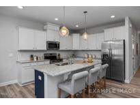 Bright kitchen features white cabinetry, stainless appliances, granite countertops, and island with seating at 3930 Well Fleet Drive, Fuquay Varina, NC 27526