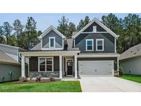 Charming two-story home featuring a two-car garage, gray siding, stone accents, and a well-manicured lawn at 7537 Percussion Dr, Apex, NC 27539