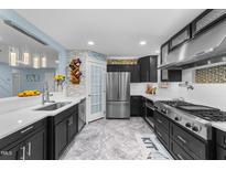 Modern kitchen features stainless steel appliances, black cabinets and a view to the living room at 5705 Katha Dr, Holly Springs, NC 27540