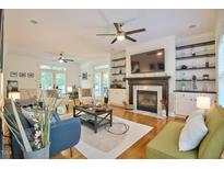 Bright living room featuring hardwood floors, fireplace, built-in bookshelves, and access to the outdoor space at 340 Andrews Store Rd, Pittsboro, NC 27312