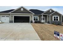 Inviting single-story home featuring a two-car garage, stone accents, neutral palette and manicured lawn at 563 Glenkirk Pl # 104, Garner, NC 27529
