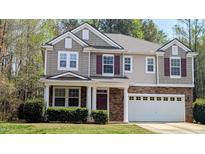 Charming two-story home features a stone facade, two-car garage and a well-manicured front lawn at 101 Clardona Way, Holly Springs, NC 27540