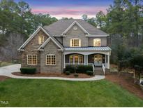 Brick two-story home with a metal roof, porch, and landscaped yard at 1201 Enderbury Dr, Raleigh, NC 27614