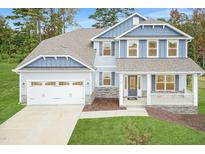 Two-story home with gray and blue siding, stone accents, and a three-car garage at 69 Streamline Ct, Lillington, NC 27546