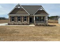 Charming single-story home featuring stone accents, and a welcoming front porch at 243 Kissington Way, Benson, NC 27504
