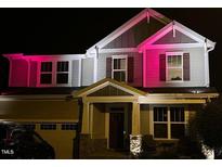 Charming two-story home with covered porch and well-maintained landscaping, illuminated by decorative lights at 2526 Snowdrop Ct, Apex, NC 27502