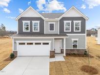 Two-story home with gray siding, white garage door, and landscaping at 31 Rolling Banks Dr, Louisburg, NC 27549