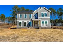 Two-story home featuring gray siding, stone accents, a covered front porch, and large windows at 367 Duncan Creek Rd # 129, Lillington, NC 27546