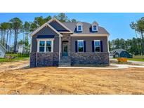 Charming two-story home with stone accents and a welcoming entrance and beautiful trees in the background at 403 Duncan Creek Rd # 131, Lillington, NC 27546