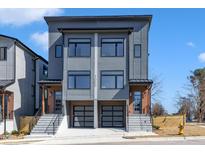 Modern townhome exterior with gray siding, black framed windows, and a two-car glass garage at 1000 Addison Pl # 102, Raleigh, NC 27610
