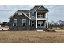 Two-story home featuring a mix of stone and siding with a covered porch, and well-maintained lawn at 85 Kissington Way, Benson, NC 27504