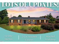 Charming brick home featuring manicured lawn, mature landscaping, and an inviting rocking chair front porch at 127 Fairfield Cir, Dunn, NC 28334