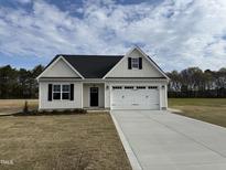 Charming single-story home with a white exterior, black door, and two car garage, set on a sunny lot at 79 Surles Landing Way, Benson, NC 27504