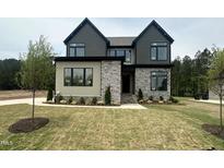 New construction featuring a stone and siding facade, complemented by a lush green lawn and manicured landscaping at 135 Cherry Bark Dr, Youngsville, NC 27596