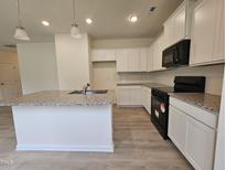 Bright kitchen features white cabinets, granite countertops, stainless steel appliances, and a central island sink at 163 Vili Dr, Broadway, NC 27505
