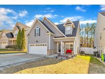 Charming two-story home with gray siding, a two-car garage, and a cozy front porch seating area at 3206 Landing Falls Ln, Raleigh, NC 27616