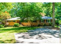 Traditional brick home with mature trees and a spacious front yard, perfect for outdoor activities at 5205 Rembert Dr, Raleigh, NC 27612