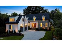 Elegant stone and white two-story home featuring a manicured lawn, dark roof, and attached garage at 1307 Mayfair Rd, Raleigh, NC 27608