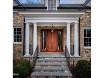 Elegant stone home featuring a covered front door with pillars, wooden door and glass sidelights at 1307 Mayfair Rd, Raleigh, NC 27608