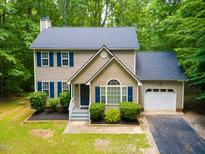 Two-story house with attached garage, nestled in a wooded area at 1554 Middle Ridge Dr, Willow Springs, NC 27592