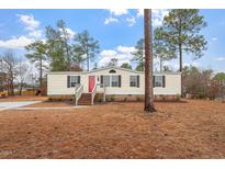 Charming single story home featuring a bright red front door, complementing the light siding and surrounding greenery at 97 Brent Wood Ct, Sanford, NC 27332